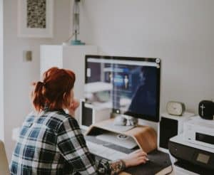 EI Online Reporting Canada - Woman in flannel shirt looking at desktop computer in modern apartment